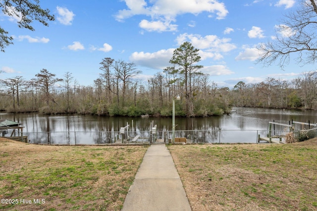 dock area with a yard, a water view, and fence