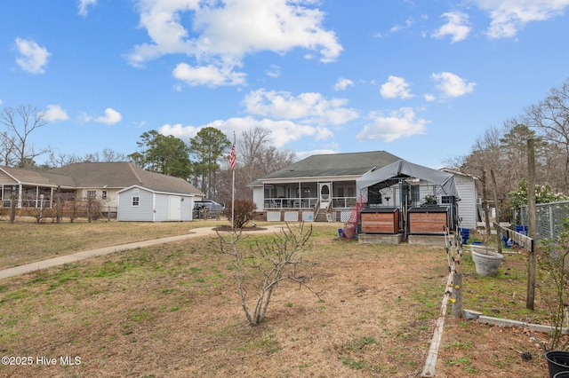 view of front of home featuring an outbuilding, a sunroom, a front yard, and fence