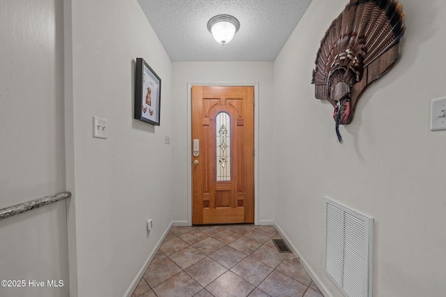 foyer with light tile patterned floors, visible vents, a textured ceiling, and baseboards