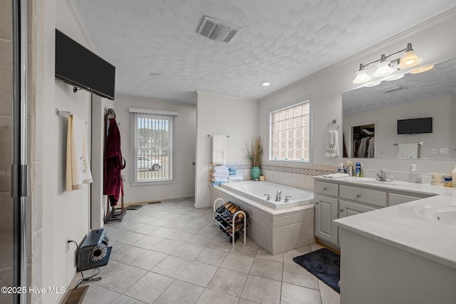 full bath featuring visible vents, double vanity, a bath, tile patterned floors, and a sink