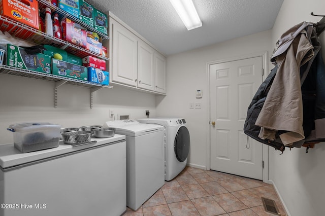 laundry area with visible vents, light tile patterned floors, cabinet space, washer and dryer, and a textured ceiling