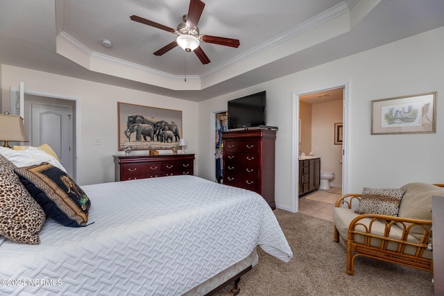 bedroom with ensuite bath, ceiling fan, a raised ceiling, light carpet, and ornamental molding