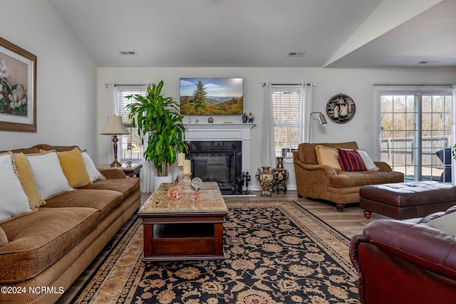 living room with a high end fireplace, hardwood / wood-style flooring, and lofted ceiling