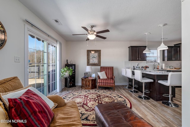 living room featuring ceiling fan, light hardwood / wood-style flooring, and sink