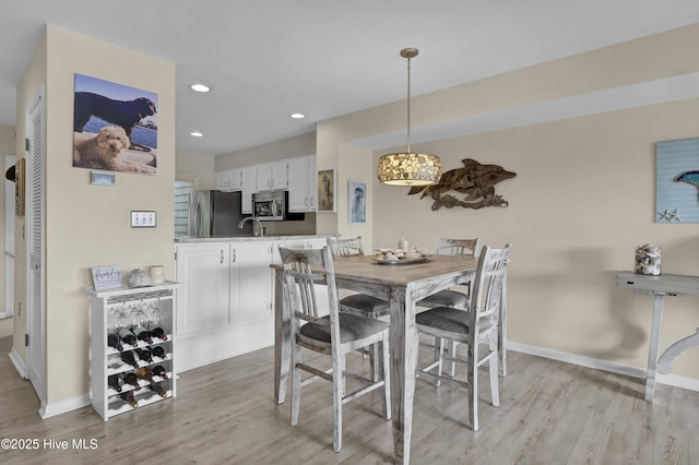 dining area with baseboards, light wood finished floors, and recessed lighting
