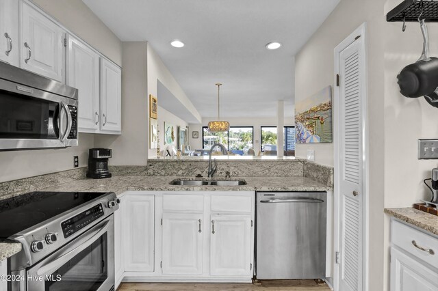 kitchen featuring white cabinetry, sink, decorative light fixtures, and appliances with stainless steel finishes