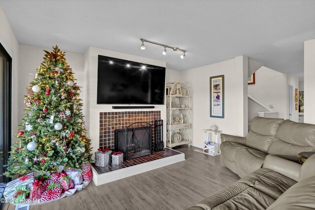 living area featuring a fireplace, stairs, and wood finished floors