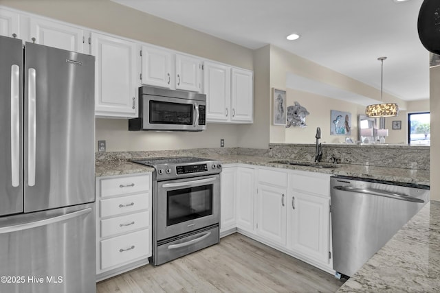 kitchen featuring white cabinets, light wood finished floors, a sink, light stone counters, and appliances with stainless steel finishes