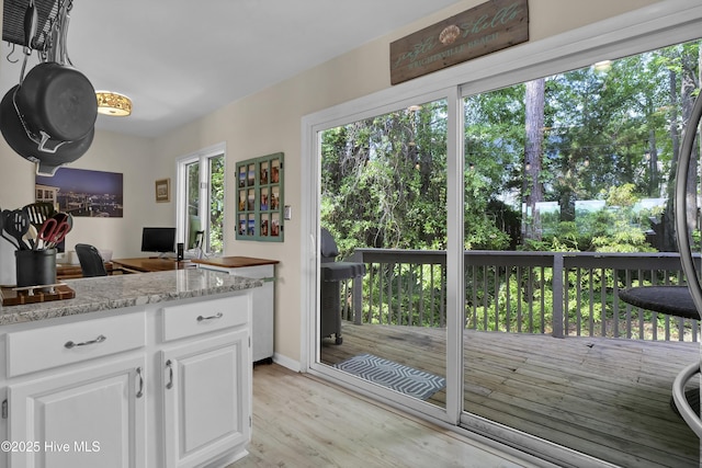 kitchen with white cabinetry, light stone countertops, and light wood-style flooring