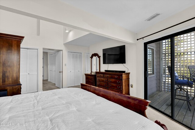 carpeted bedroom featuring visible vents, two closets, and access to outside