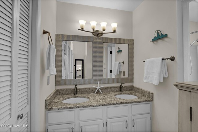 bathroom with a closet, double vanity, and a sink