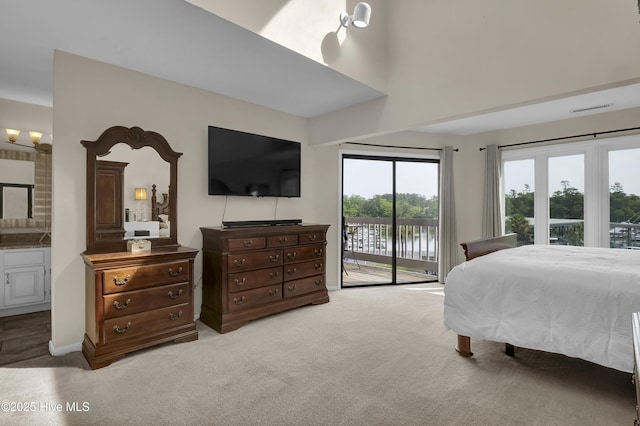 bedroom featuring ensuite bathroom, a high ceiling, carpet, and access to exterior