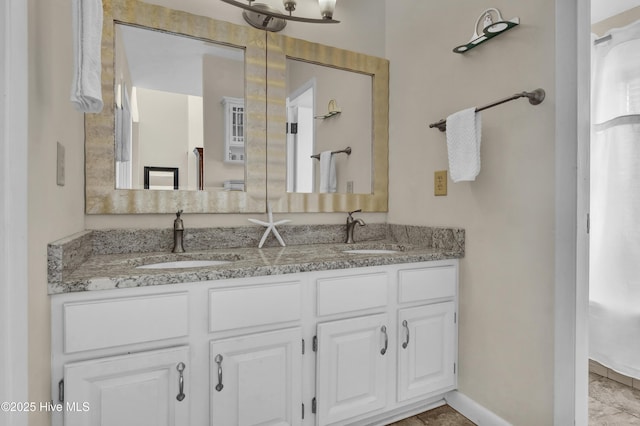 full bathroom with baseboards, a sink, and double vanity