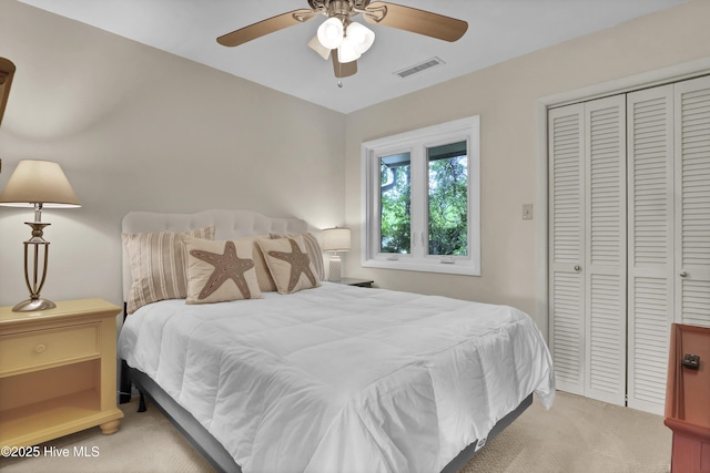 bedroom with a closet, ceiling fan, visible vents, and light carpet