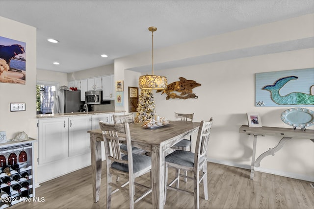 dining area featuring recessed lighting, beverage cooler, a textured ceiling, and light wood-style flooring