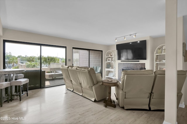 living room featuring a tiled fireplace, wood finished floors, and rail lighting