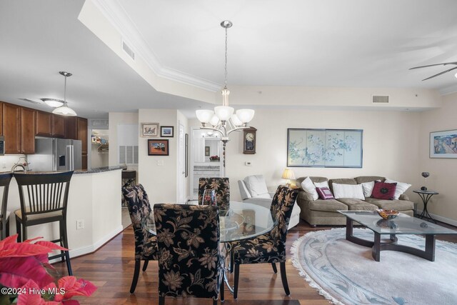 dining room featuring ceiling fan with notable chandelier, dark hardwood / wood-style flooring, ornamental molding, and a tray ceiling