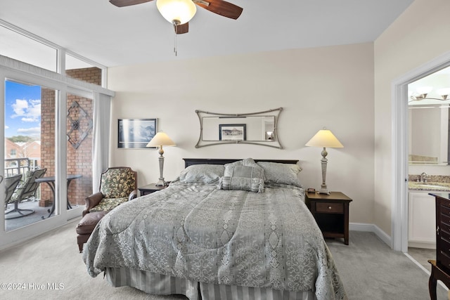 carpeted bedroom with ceiling fan, access to exterior, sink, and ensuite bath