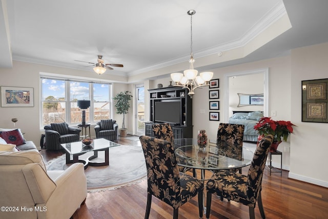 dining space featuring ceiling fan with notable chandelier, dark hardwood / wood-style floors, a raised ceiling, and crown molding