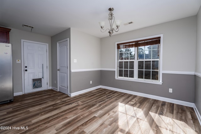 unfurnished dining area with dark hardwood / wood-style floors and an inviting chandelier