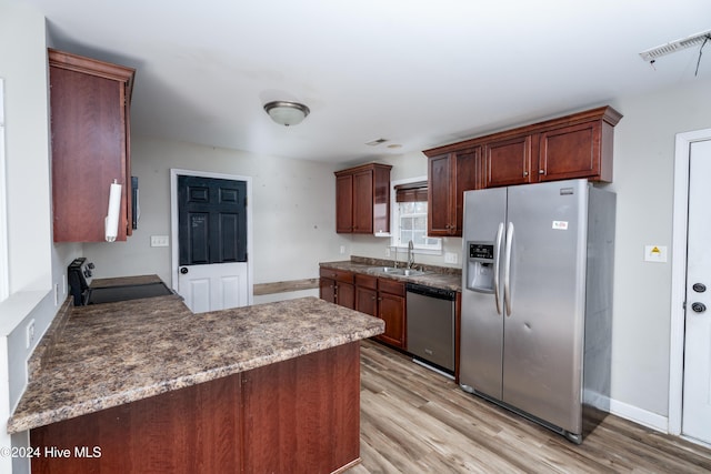 kitchen featuring kitchen peninsula, sink, light wood-type flooring, and appliances with stainless steel finishes