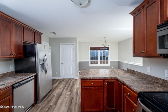 kitchen featuring appliances with stainless steel finishes, light hardwood / wood-style floors, and a notable chandelier