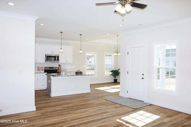 kitchen featuring appliances with stainless steel finishes, white cabinetry, a kitchen island with sink, and plenty of natural light