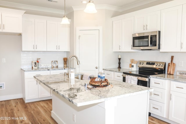 kitchen with stainless steel appliances, white cabinetry, and an island with sink