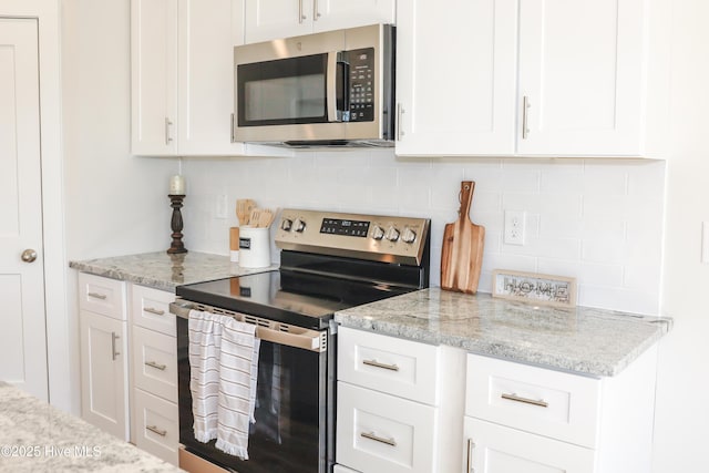 kitchen with white cabinets, light stone countertops, stainless steel appliances, and tasteful backsplash