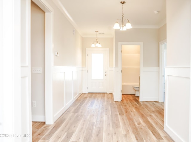 foyer entrance featuring crown molding, a chandelier, and light hardwood / wood-style floors