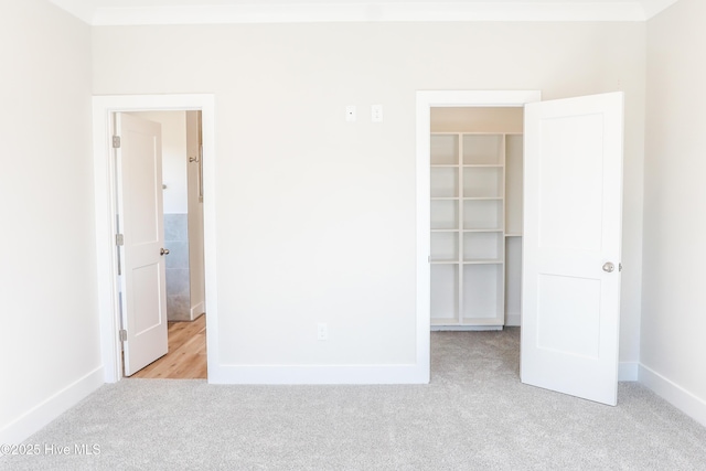 unfurnished bedroom with a walk in closet, light colored carpet, and a closet