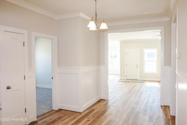 corridor featuring a notable chandelier, crown molding, and light hardwood / wood-style flooring