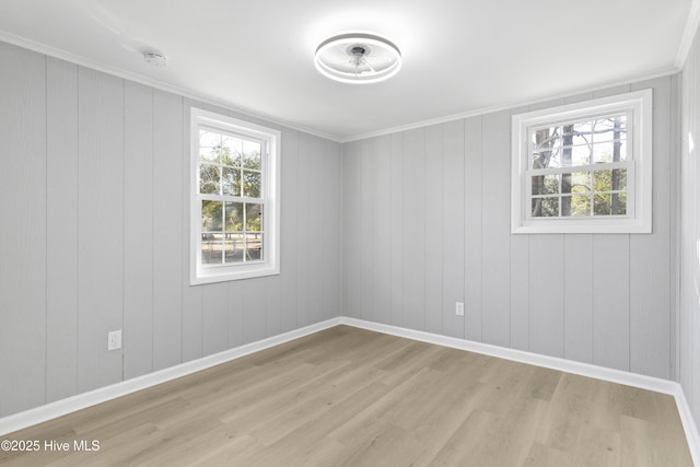 empty room with plenty of natural light, light hardwood / wood-style floors, and crown molding