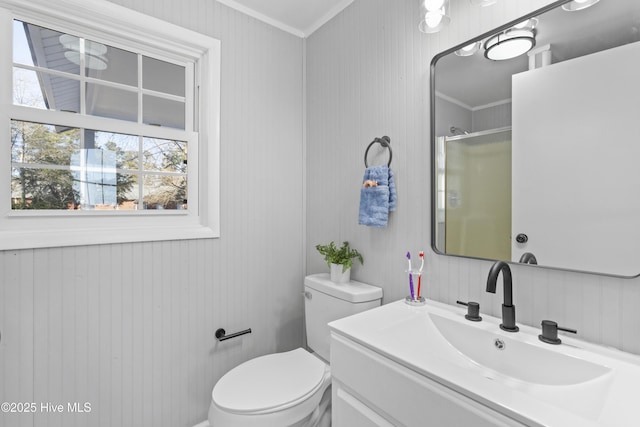 bathroom featuring vanity, a shower with door, wooden walls, crown molding, and toilet