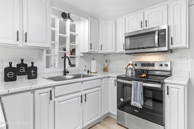 kitchen with light stone counters, white cabinetry, sink, and appliances with stainless steel finishes