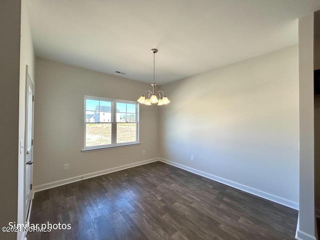 spare room with dark wood-type flooring and a chandelier