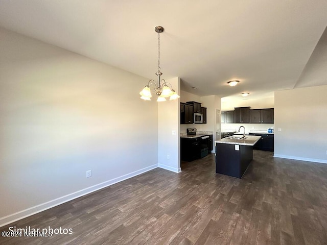 kitchen with appliances with stainless steel finishes, a kitchen island with sink, dark wood-type flooring, pendant lighting, and a chandelier