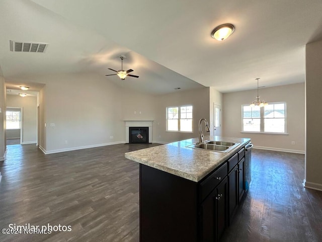 kitchen featuring a center island with sink, pendant lighting, sink, and dark wood-type flooring