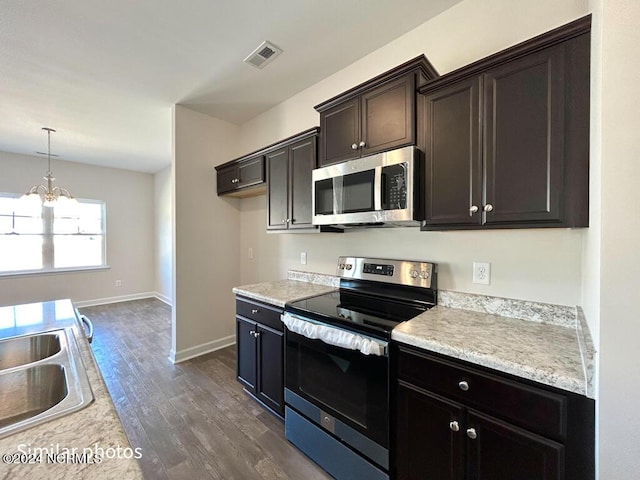 kitchen with dark hardwood / wood-style floors, dark brown cabinetry, stainless steel appliances, and a chandelier