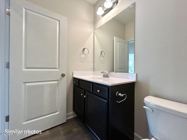 bathroom featuring toilet, vanity, and hardwood / wood-style flooring