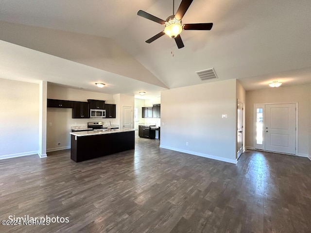 kitchen featuring vaulted ceiling, a center island with sink, dark hardwood / wood-style floors, and appliances with stainless steel finishes