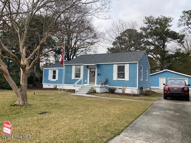 view of front of house featuring a garage, an outbuilding, and a front yard