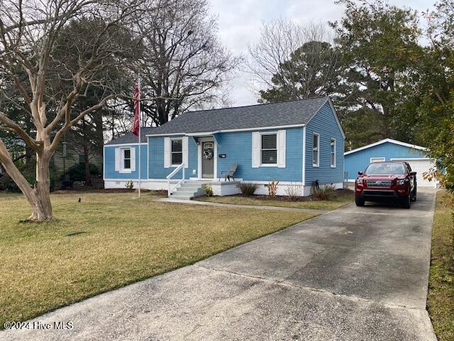 view of front facade with an outbuilding, a front lawn, and a garage