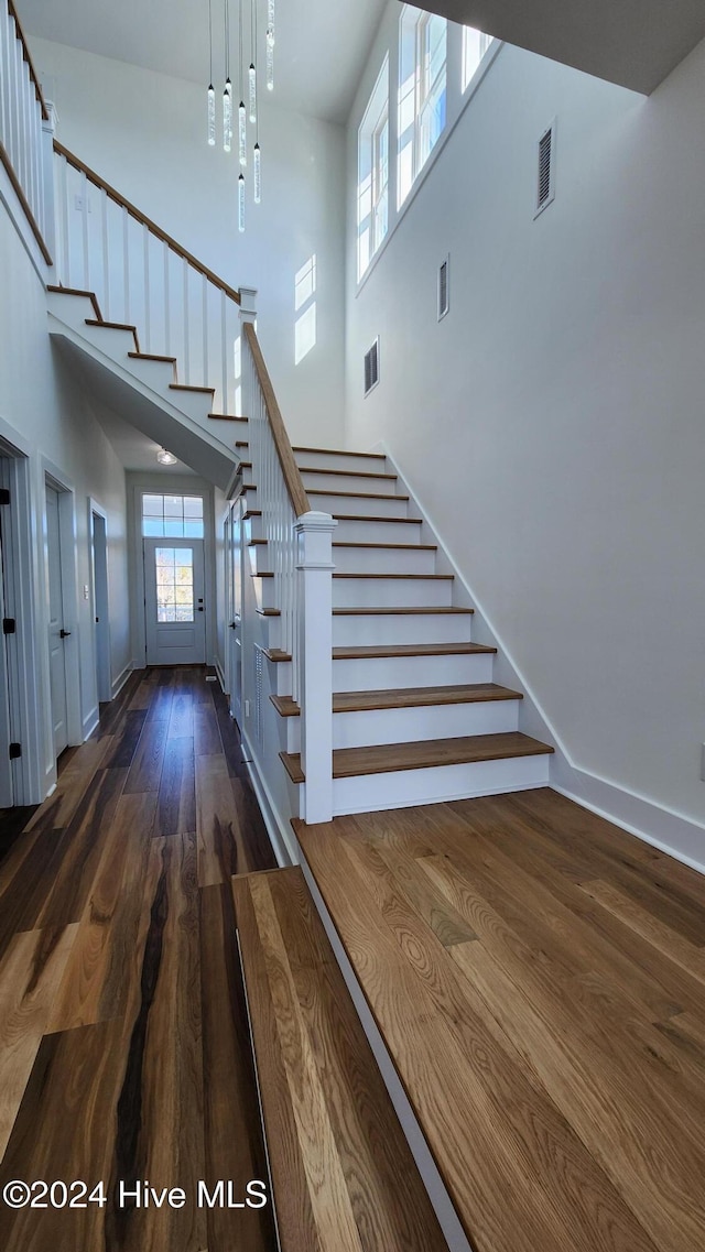 staircase featuring a high ceiling and hardwood / wood-style flooring