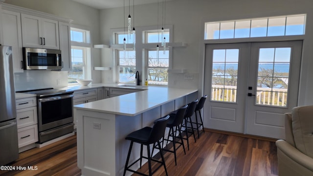 kitchen featuring white cabinets, a kitchen breakfast bar, kitchen peninsula, and appliances with stainless steel finishes