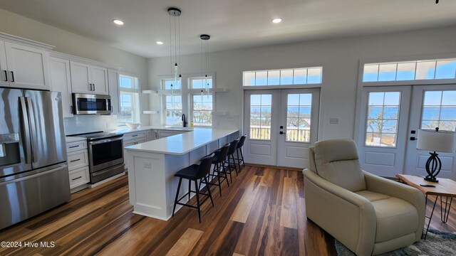 kitchen featuring kitchen peninsula, appliances with stainless steel finishes, french doors, a breakfast bar, and white cabinets