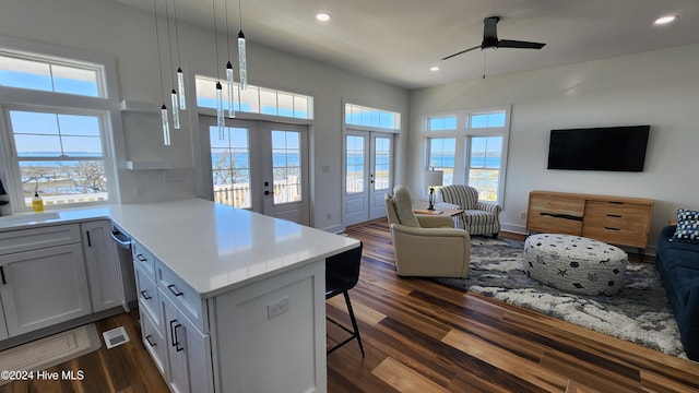 kitchen with french doors, dark hardwood / wood-style floors, kitchen peninsula, pendant lighting, and a breakfast bar