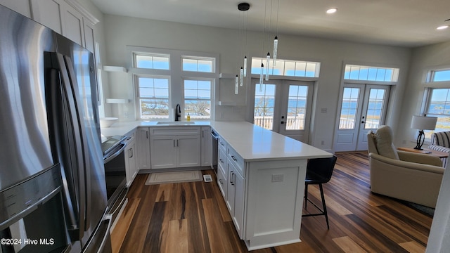 kitchen featuring kitchen peninsula, french doors, decorative light fixtures, white cabinetry, and stainless steel refrigerator