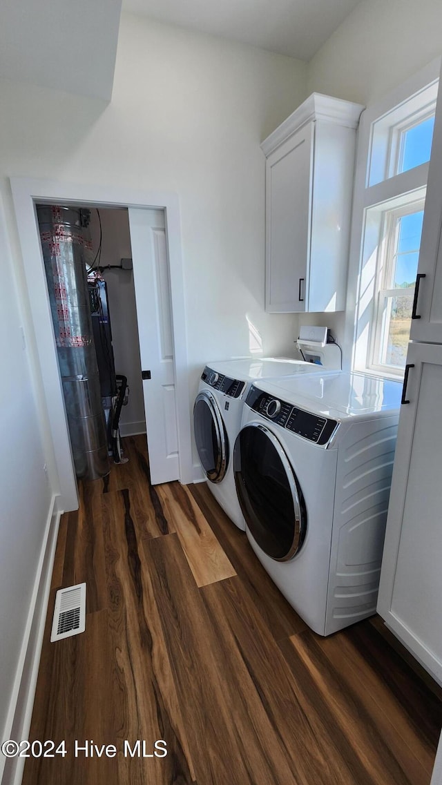 laundry room with cabinets, independent washer and dryer, dark hardwood / wood-style floors, and water heater