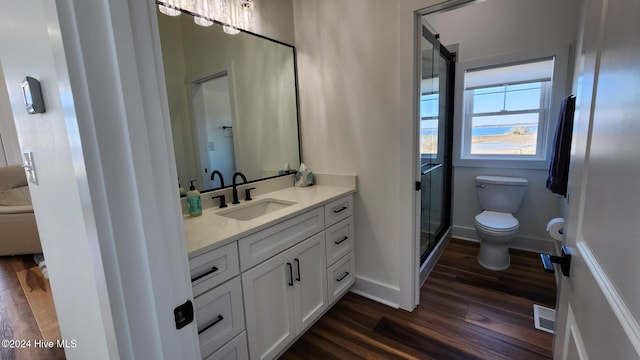 bathroom featuring hardwood / wood-style floors, vanity, toilet, and a shower with door